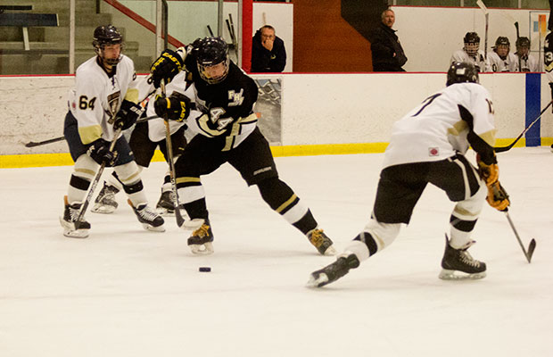 Junior Finnish exchange student Tuomas Hyypia pushes the puck through FZE's Jarrod Ouzts (left) and Cody Freant (right)
